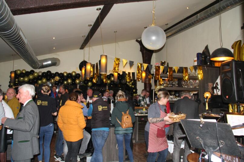 Die 10 Jahres Feier ist in vollem Gange, Besucher lehnen an Stehtischen und der Raum ist aufwendig in schwarz und gold geschmückt